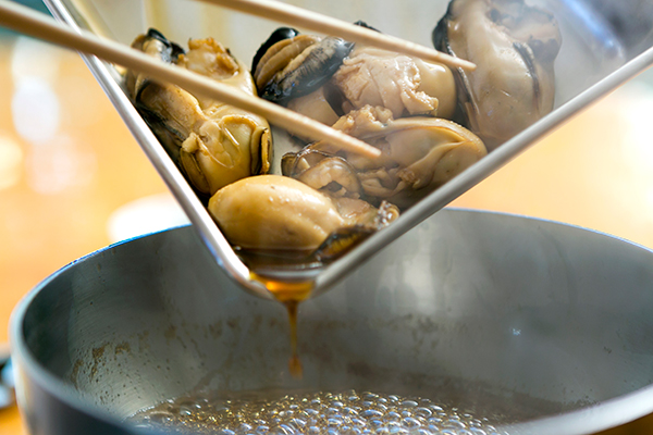牡蠣に火入れするときは、下ごしらえと火入れがポイント。湯通しをしてアクを取ってから味付けを 開始。醤油ベースのタレに牡蠣を入れ、沸騰したらバットに引き上げ、余熱で火を入れます。それを３〜４回繰り返します。低温調理で、牡蠣の食感と本来の味を生かします。